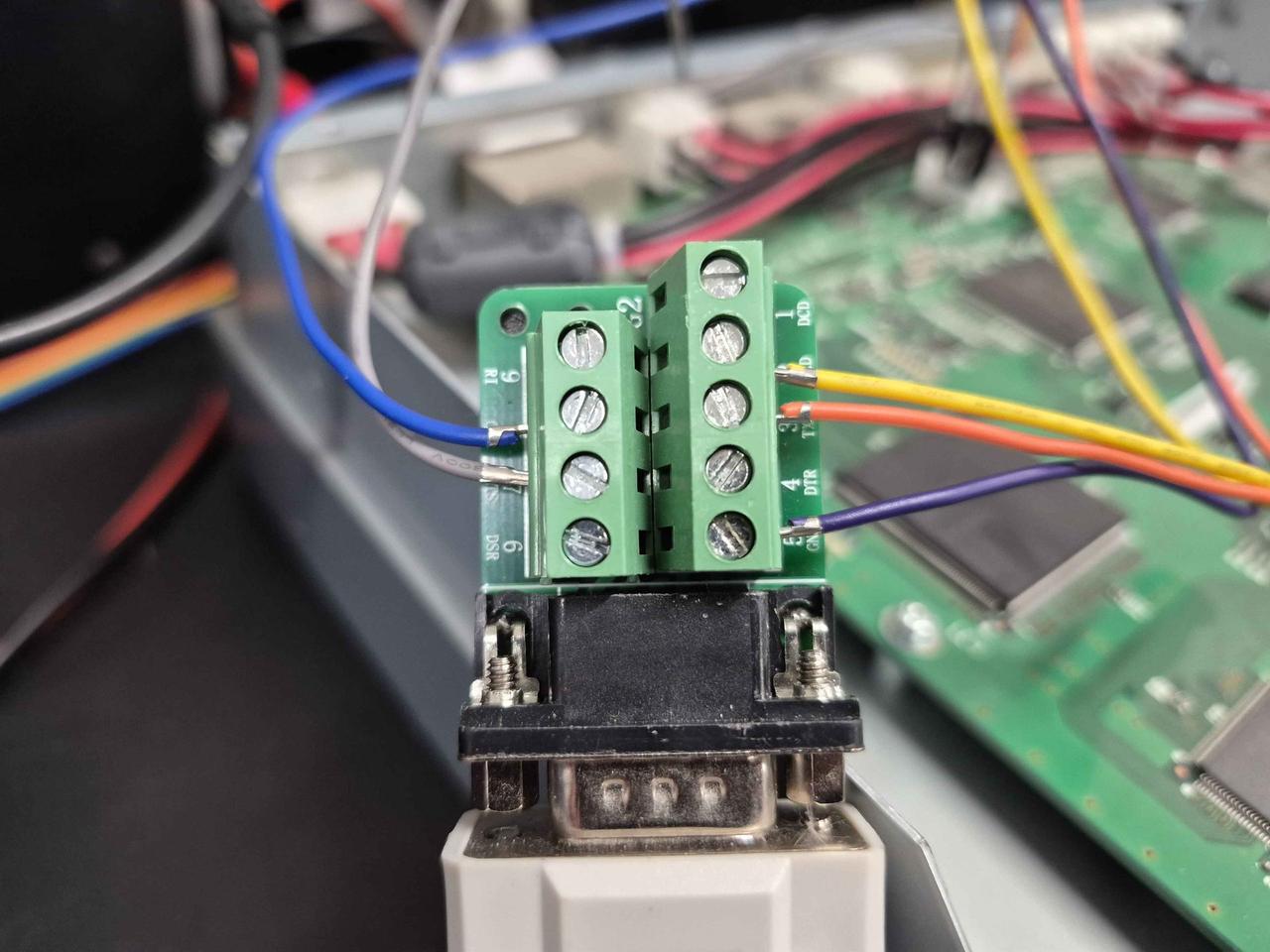 A DB9 male connector with a screw-terminal breakout board on top. Wires from the J6 cable land on pins 2 (RxD), 3 (TxD), 5 (GND), 7 (RTS), and 8 (CTS) of the breakout.